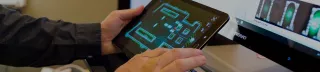 Image of hands holding a tablet playing a game